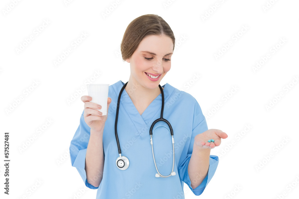 Female doctor holding a plastic cup and blue pills while looking Female doctor holding a plastic cup and blue pills while looking