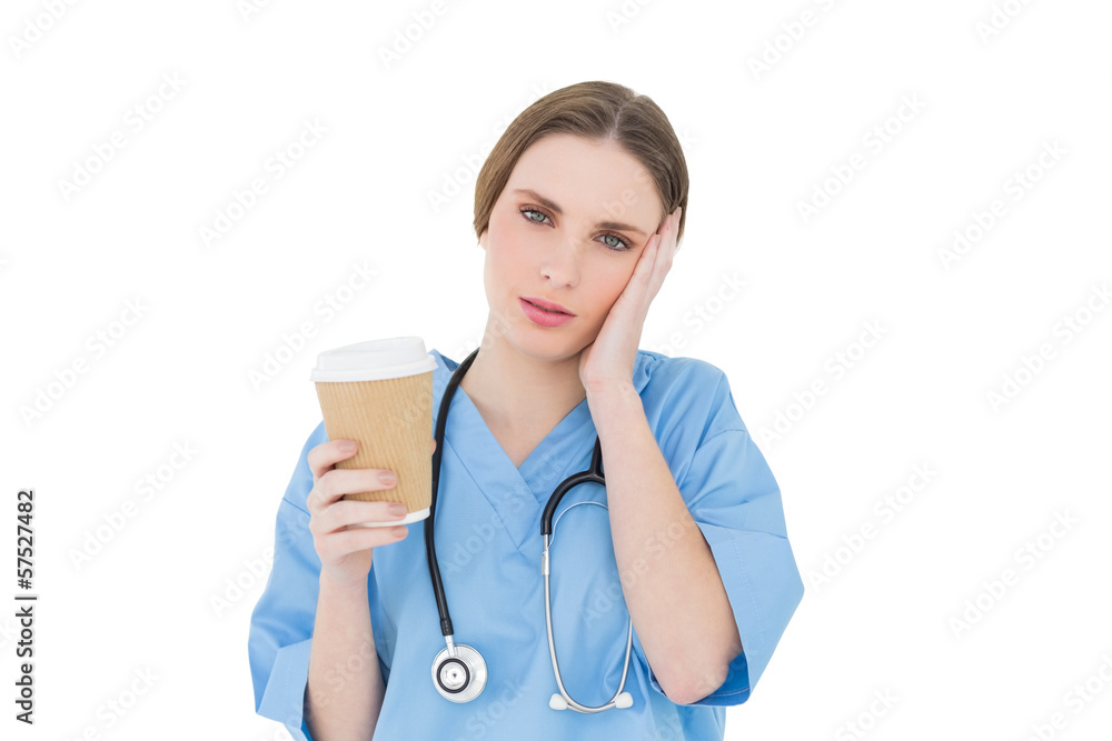 Female doctor holding a coffee mug and lifting her hand to her f Female doctor holding a coffee mug and lifting her hand to her f