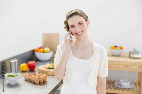 Content young woman honing while standing in kitchen