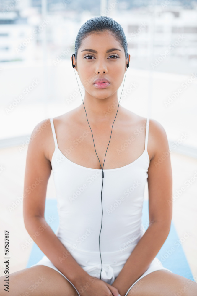Frowning toned brunette listening to music