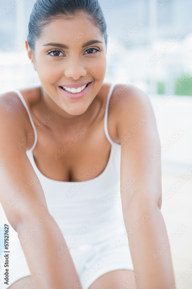 Portrait of smiling toned brunette sitting on floor Portrait of smiling toned brunette sitting on floor