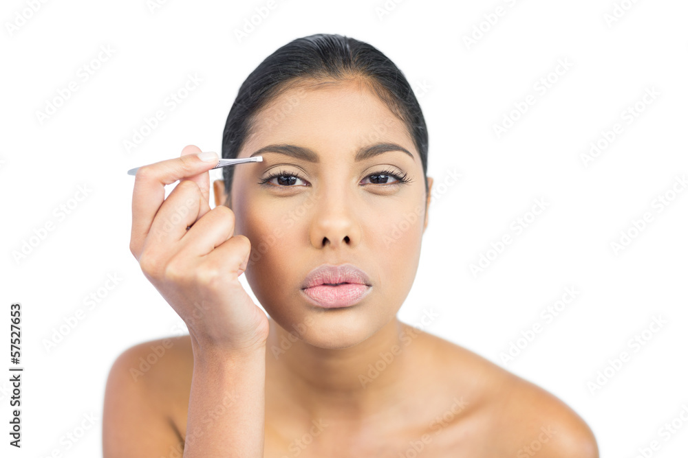 Serious nude brunette using tweezers