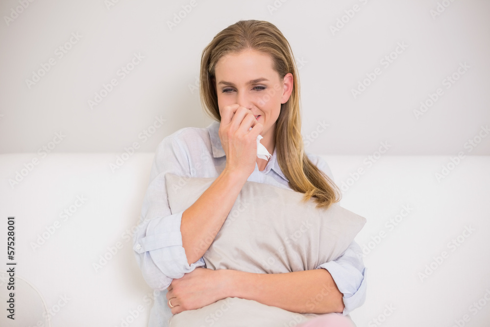 Upset casual blonde sitting on couch crying Upset casual blonde sitting on couch crying
