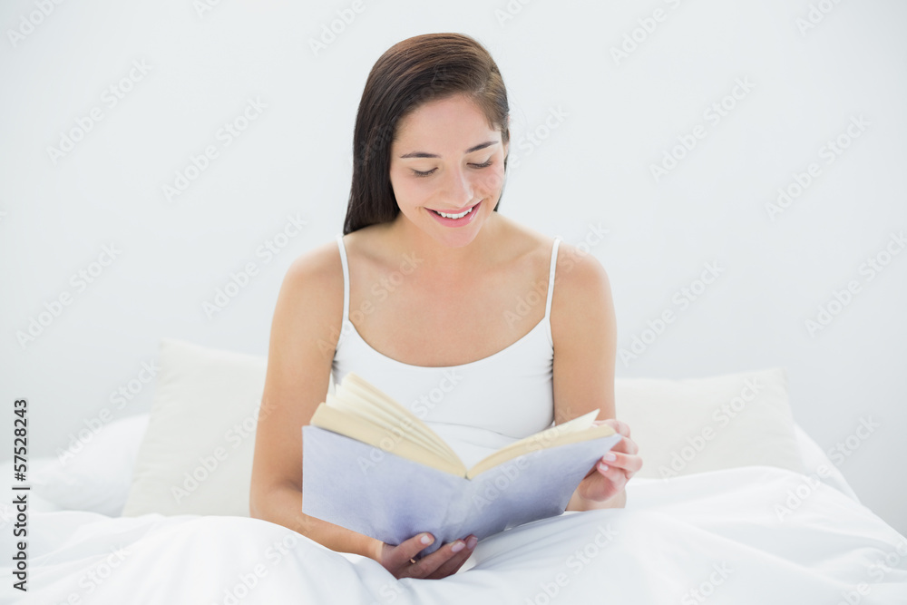 Smiling woman reading a book in bed Smiling woman reading a book in bed