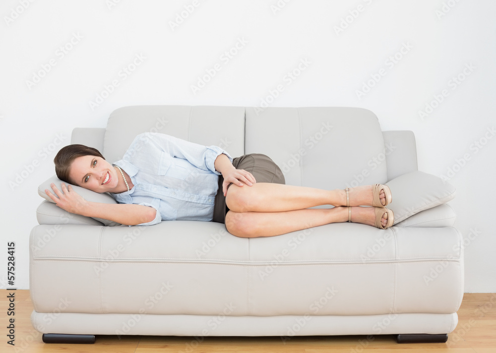 Smiling well dressed young woman relaxing on sofa Smiling well dressed young woman relaxing on sofa
