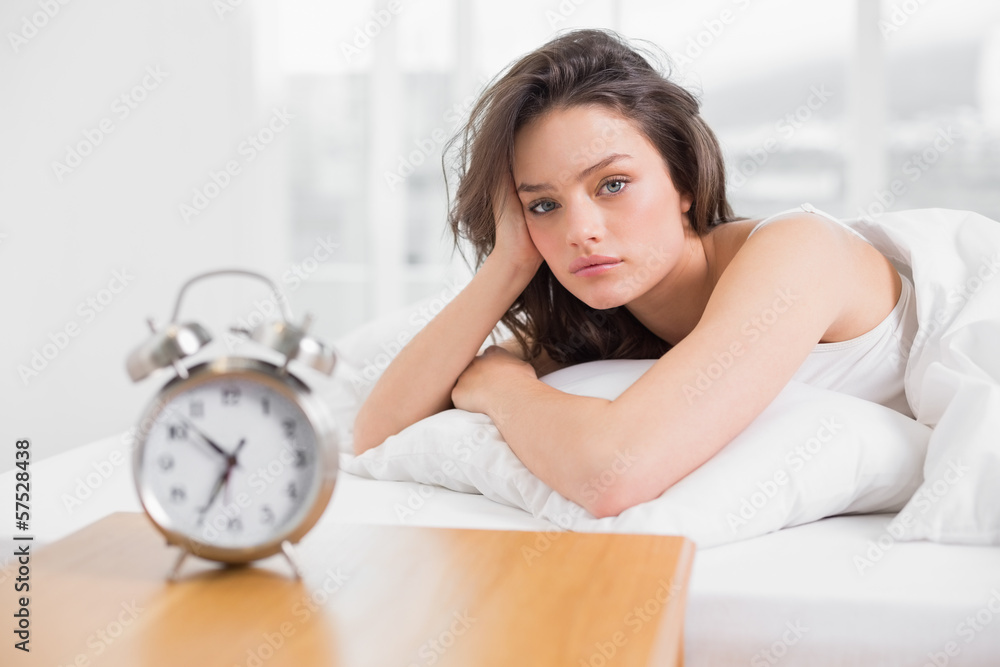 Beautiful woman in bed with alarm clock on bedside table Beautiful woman in bed with alarm clock on bedside table