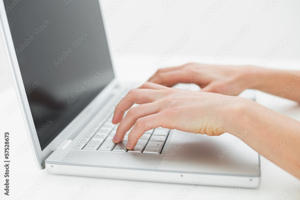 Close-up of hands typing on laptop keyboard