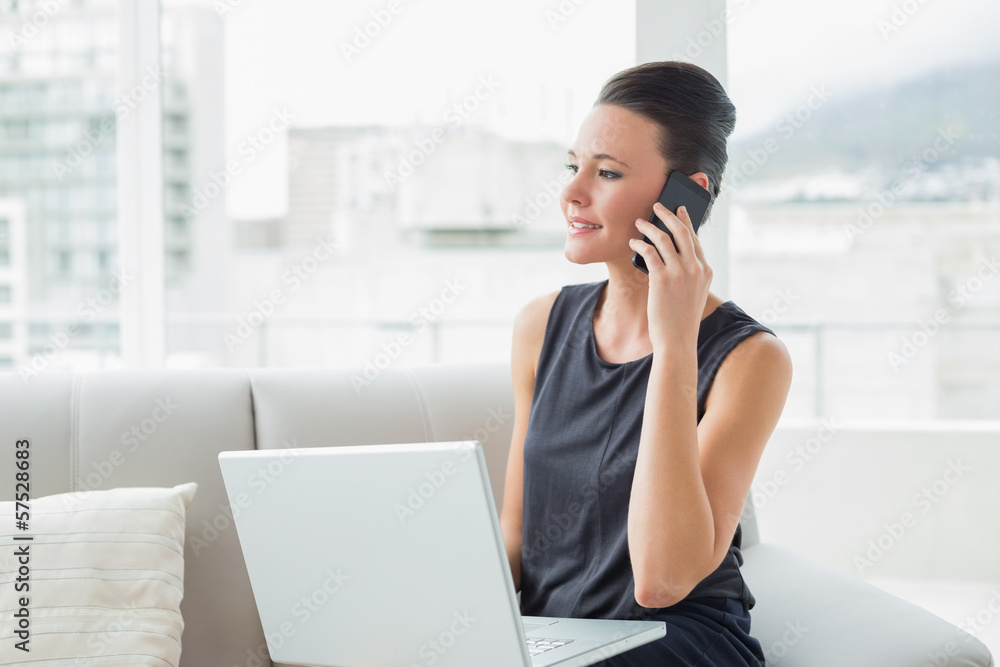 Beautiful well dressed woman using laptop and cellphone on sofa Beautiful well dressed woman using laptop and cellphone on sofa