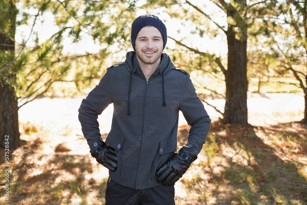 Smiling young man in warm clothing standing in forest Smiling young man in warm clothing standing in forest