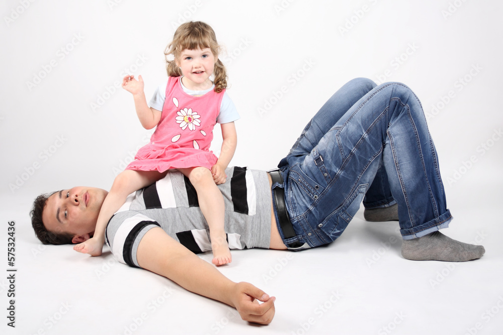 Happy father lies on floor and little happy daughter sits on his Happy father lies on floor and little happy daughter sits on his