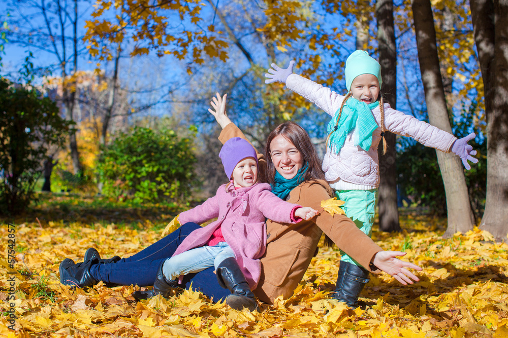 Fototapeta premium Little girls and young mother in autumn park have fun