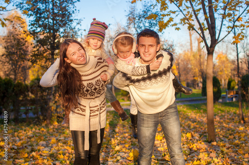 Family of four with two kids having fun in autumn park on a