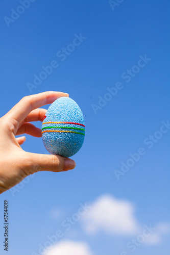 Bright blue Beautiful Easter egg in hand on background of blue