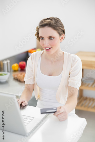 Astonished gorgeous woman using her notebook for home shopping i