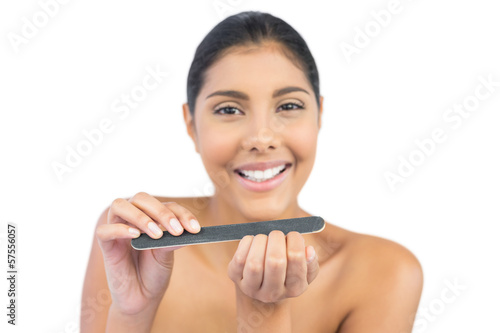 Smiling nude brunette using nail file