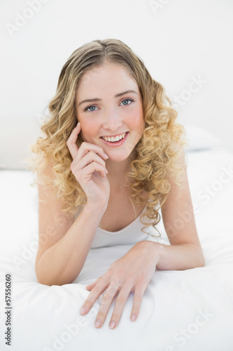 Pretty happy blonde lying on bed looking at camera