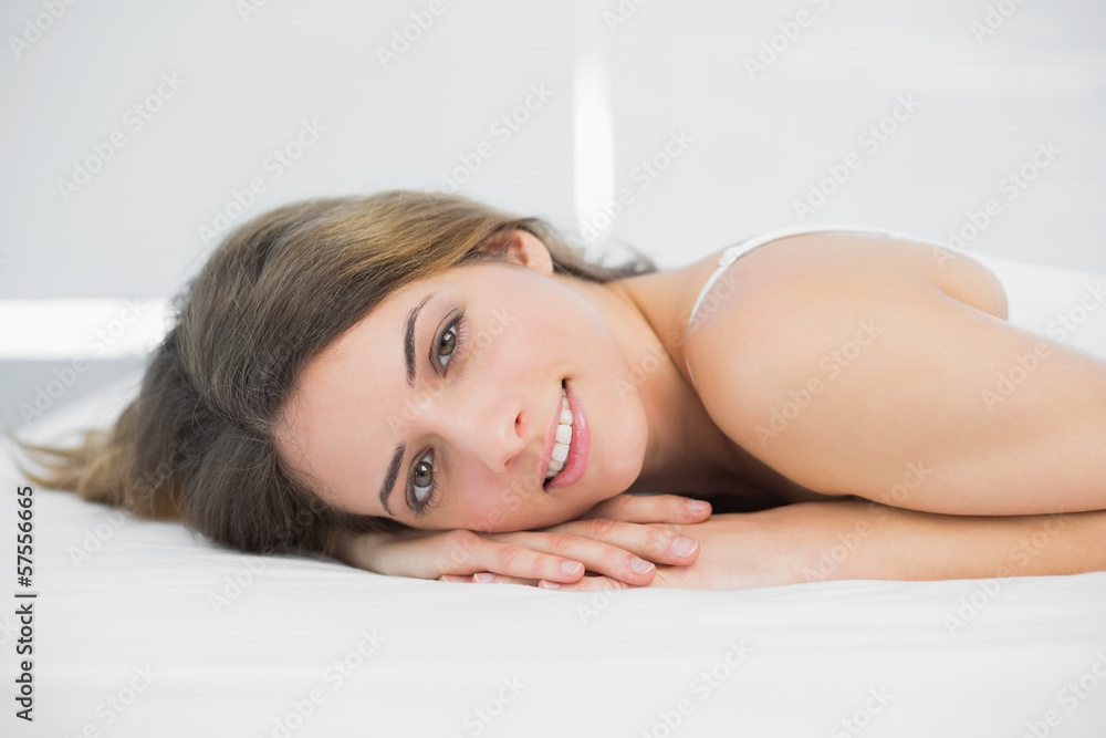 Content brunette woman smiling at camera lying on her bed Content brunette woman smiling at camera lying on her bed
