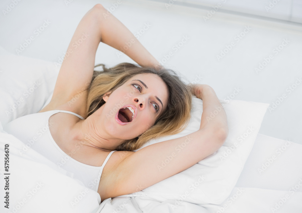 Obraz premium Pretty brunette woman yawning lying on her bed