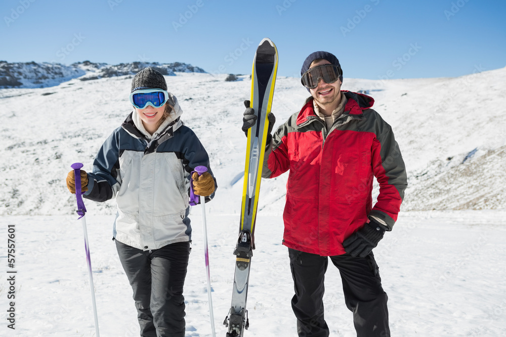Portrait of a smiling couple with ski equipment on snow