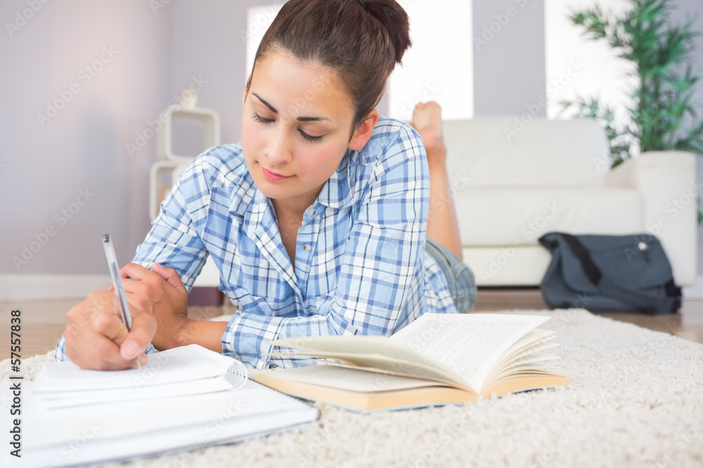 Gorgeous brunette student doing homework lying on the floor Gorgeous brunette student doing homework lying on the floor