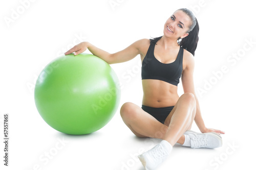 Cute slender woman posing sitting on the floor next to an exerci