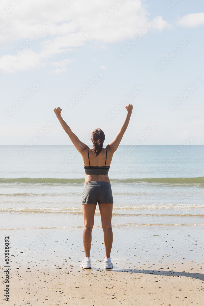 Rear view of slim young woman raising her arms standing on the b Rear view of slim young woman raising her arms standing on the b