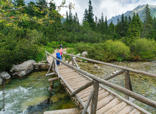 Stream and family on wooden bridge (High Tatras, Slovakia) .