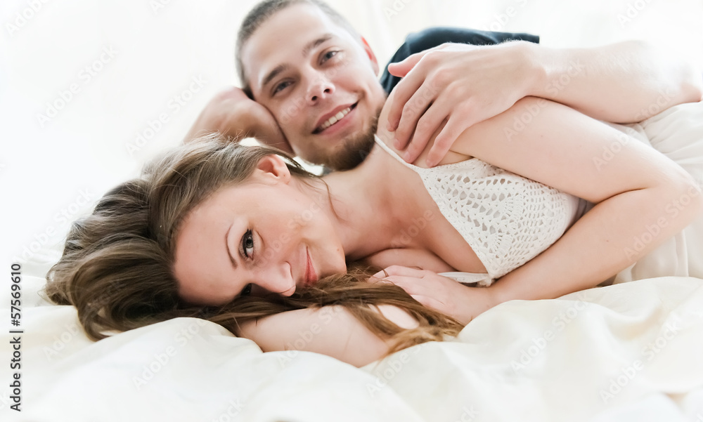 Lovely couple hugging on their bed at home