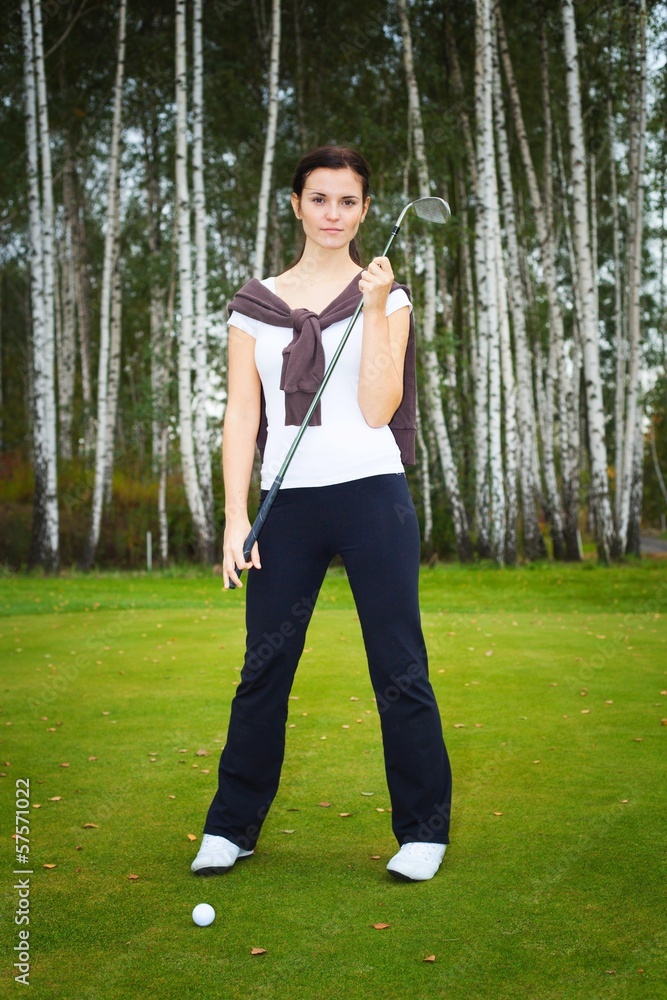 Woman golf player posing on green with club and ball Woman golf player posing on green with club and ball