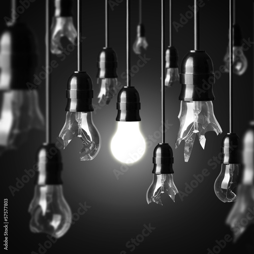 idea concept with broken bulbs and one glowing bulb
