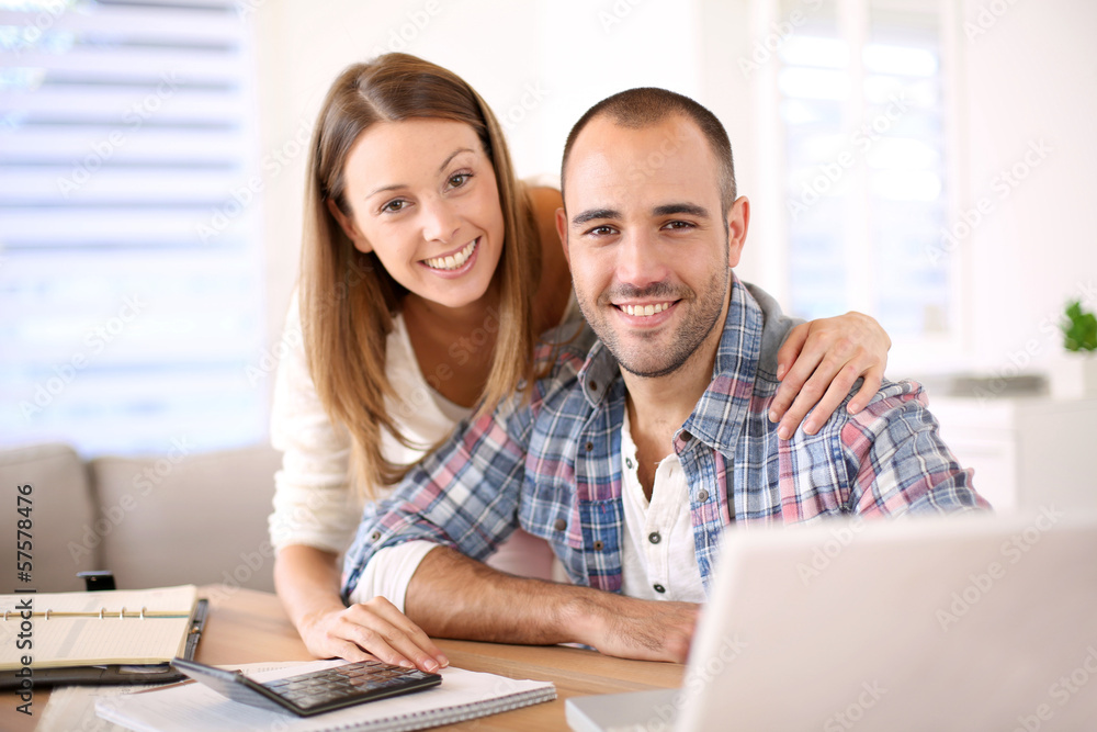 Young cheerful couple calculating savings for home investment Young cheerful couple calculating savings for home investment