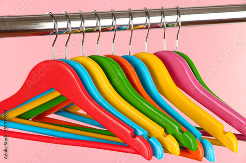 Colorful clothes hangers on pink background