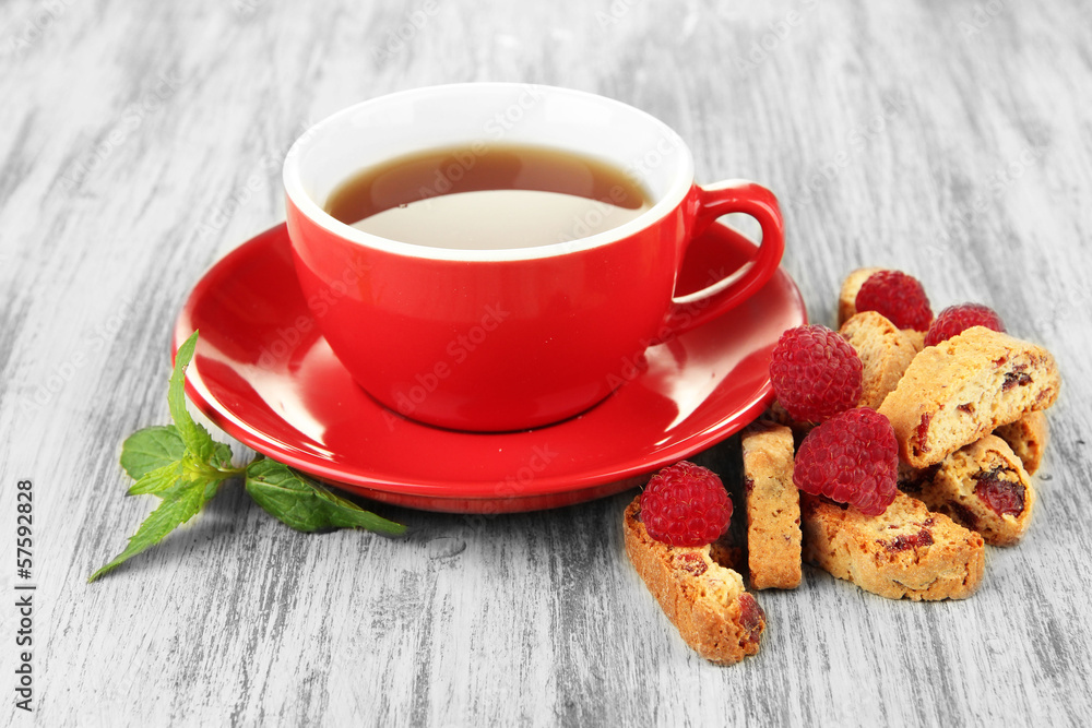 Cup of tea with cookies and raspberries on table close-up