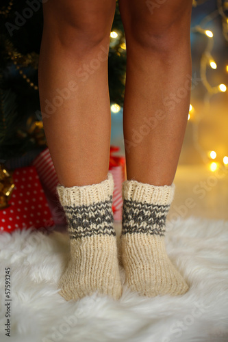 Legs in socks near Christmas tree on carped