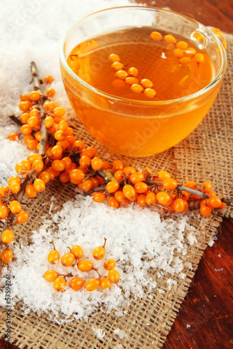 Branches of sea buckthorn with tea and sackcloth close up photo