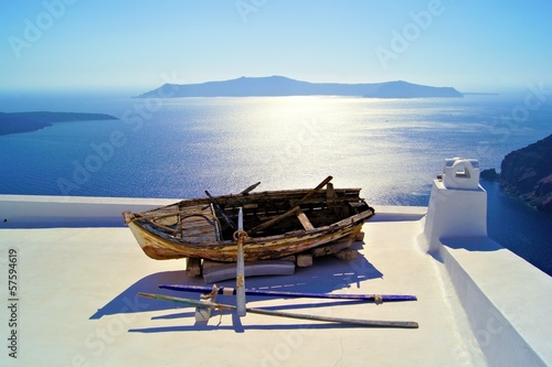 Old wooden boat on the white rooftops of Santorini, Greece