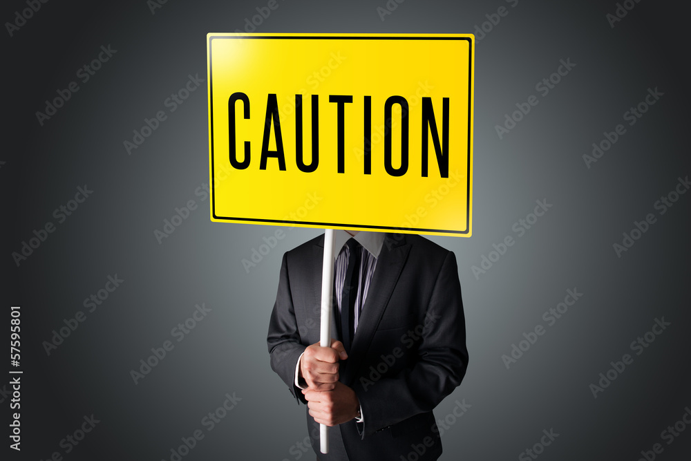 Businessman holding a caution sign Businessman holding a caution sign