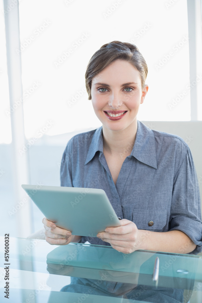 Beautiful businesswoman holding her tablet sitting at her desk Beautiful businesswoman holding her tablet sitting at her desk