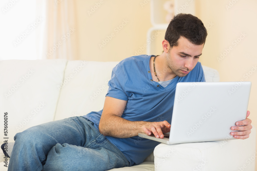 Casual calm man sitting on couch using laptop Casual calm man sitting on couch using laptop