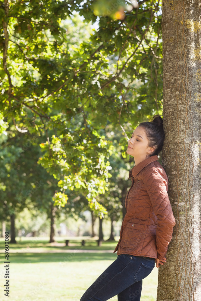Attractive woman leaning against a tree with closed eyes Attractive woman leaning against a tree with closed eyes