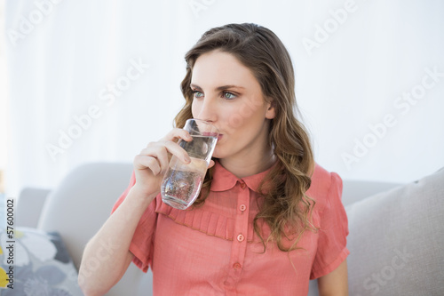 Beautiful pregnant woman drinking glass of water sitting on couc