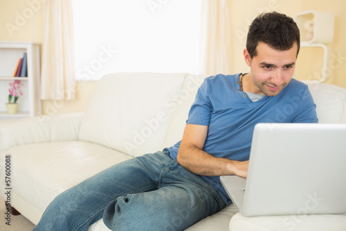 Casual attractive man sitting on couch using laptop