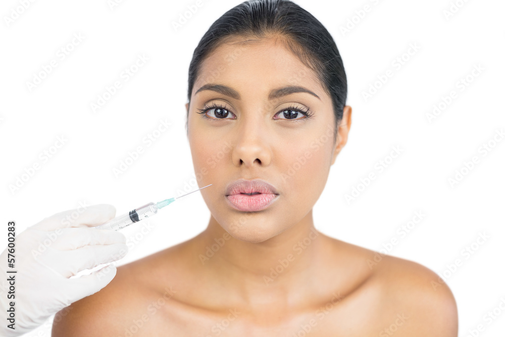 Unsmiling nude brunette holding injection looking at camera