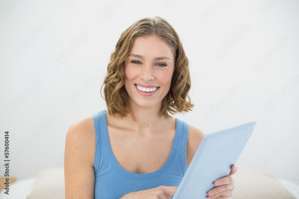 Gorgeous laughing woman holding her tablet while smiling at came Gorgeous laughing woman holding her tablet while smiling at came