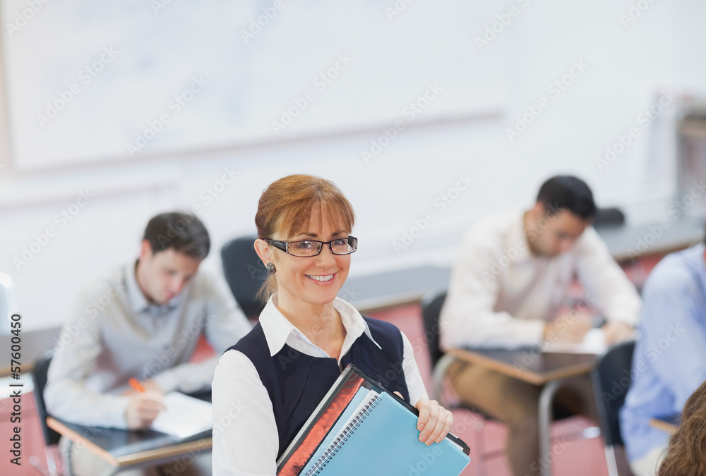 Fototapeta premium Female teacher posing in her classroom holding some files