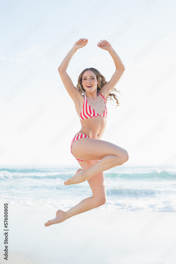 Young woman jumping on the beach wearing a red bikini Young woman jumping on the beach wearing a red bikini