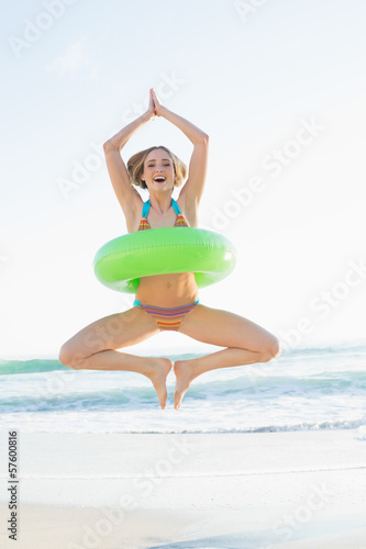 Sweet woman holding a rubber ring jumping on beach