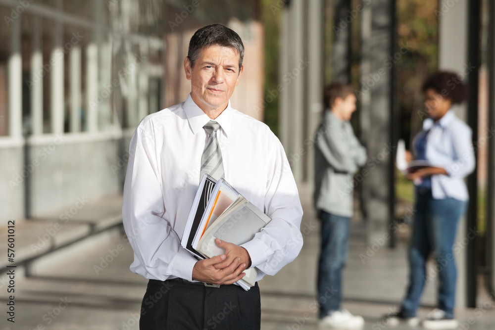 Confident Professor With Books Standing On College Campus Confident Professor With Books Standing On College Campus