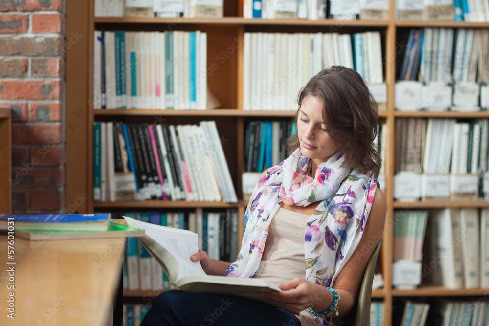 Female student reading a book in the library Female student reading a book in the library