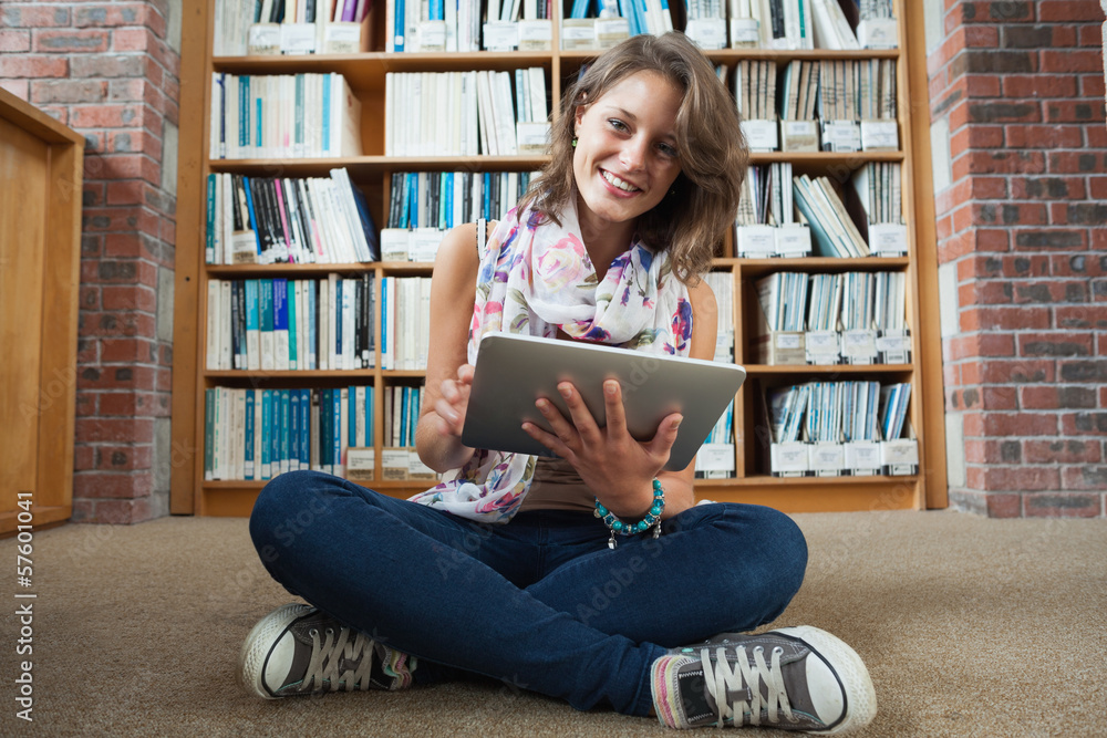 Happy student against bookshelf with tablet PC on the library fl Happy student against bookshelf with tablet PC on the library fl